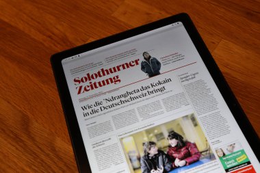 Solothurn, İsviçre, 03.01.2022: Üzerinde dijital bir gazete indirilmiş ahşap masa üzerindeki bir tablet.