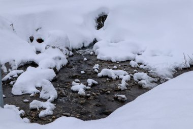İsviçre 'nin Churwalden şehrinde karların içinden akan küçük bir nehir.