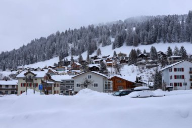 Kışın İsviçre 'nin Churwalden kentindeki sisli, karlı araziye ve Churwalden evlerine bakın.