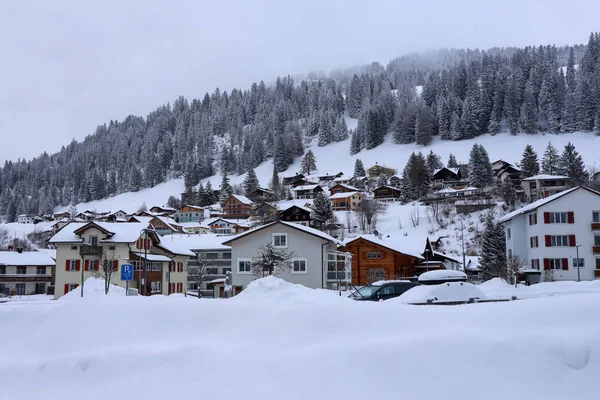 Blick auf die neblig-verschneite Landschaft und die Häuser von Churwalden, Schweiz im Winter Stockbild