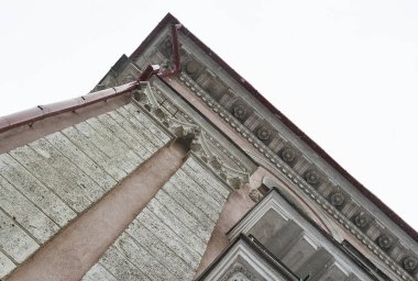 Binanın ön cephesinin bir parçası eğimli bir açıyla, Cornice üzerinde gül şeklinde sıva, renksiz bir kış gökyüzü karşı