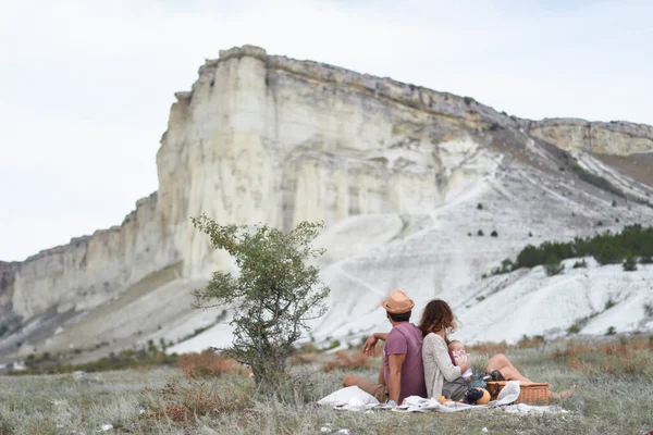 Piknik sırasında güneşli bir yaz gününde görkemli beyaz bir kayanın arka planına karşı durabilen bir aile.