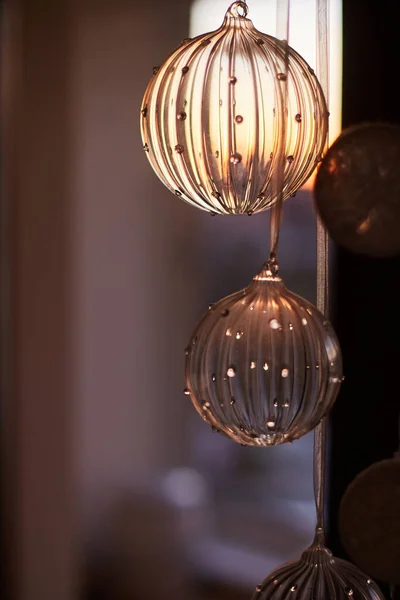 Bir çelenk içinde asılı cam toplar, bir pencerenin bulanık arka planında ve gün batımında