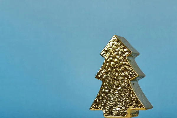 Üniformalı mavi arka planda altın ağaç şeklinde bir Noel oyuncağı