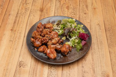 Japon teriyaki soslu doğranmış tavuk marul, susam tohumu ve gelincikle süslenmiş.