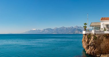 Türkiye 'nin Antalya sahillerinde güzel plajlar ve yüksek karla kaplı dağlarla panoramik. Bahçeli ve palmiyeli ceylan.