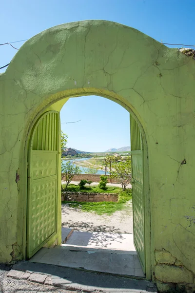 金属製のドアだけでなく それをサポートする石の壁に緑を描いた 中庭への入り口と川への視点を持つイスラム建築 — ストック写真