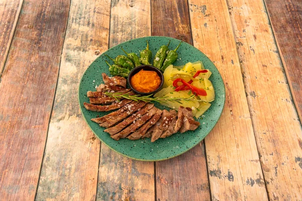 İspanyol tarifi, fırında patates, kavrulmuş biber ve gevrek deniz tuzu ve biberiyeli kızarmış Padron biberi ile birlikte İber domuz tüyü. 