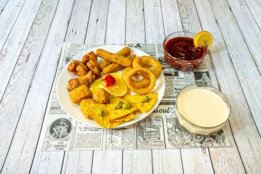 Tavuk kanatları, soğan halkaları, Guacamole Tortilla cipsi, Nuggets ve soslu peynirli çubuklar.
