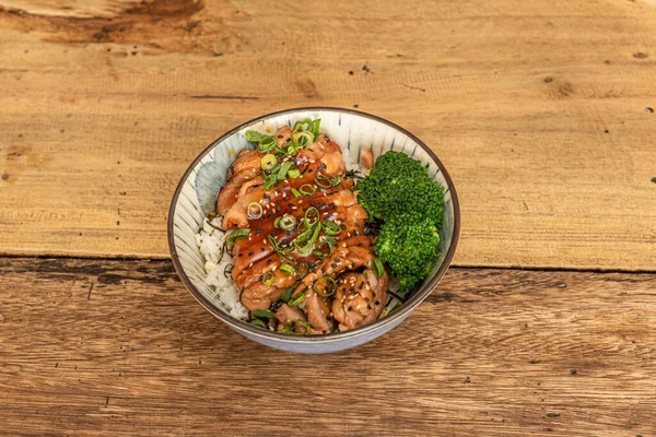 Bowl with fried chicken fillet with teriyaki sauce, sesame and poppy seeds, white rice and broccoli cooked with fresh chives