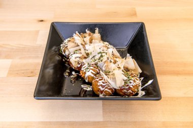 Japon ahtapotlu siyah tabak takoyaki ve soslu füme ton balığı dilimleri.