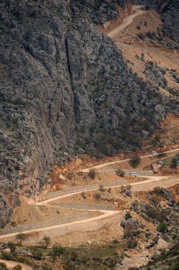 Çok dik toprak pist. Birkaç minibüs dik dağlar arasındaki geçitten geçiyor.