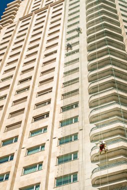 Bir gökdelenin beyaz mermer cephesini tamir eden işçiler.