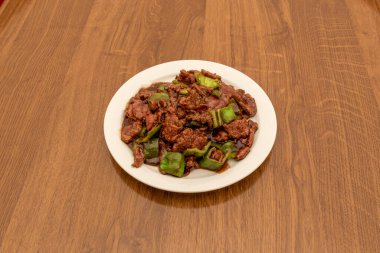 Kızarmış yeşil biberli biftek, istiridye sosu ve beyaz tabakta soya soslu popüler Çin restoranı tarifi..