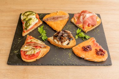 Norveç somonu, ratatouille peyniri, ançüezli krema, İber jambonu, İspanyol meze restoranında servis edilen keçi peyniri.