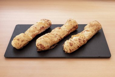 Kızarmış peynir çubukları siyah tabakta.