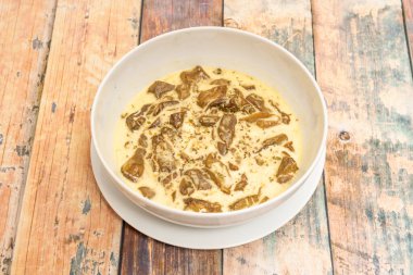 Boletus edulis güveci, ahşap masada beyaz kasede krem peynirli.