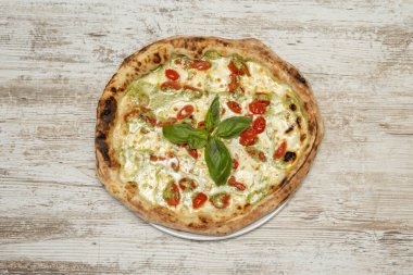 Peynirli mozzarella, yeşil soslu, kiraz domatesli ve fırında fesleğen yapraklı pizza.