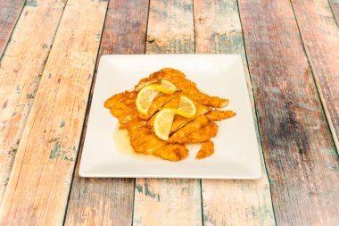 Beyaz tabakta Çin limon sosuyla servis edilen doğranmış panko parçalanmış tavuk göğsü filetoları.