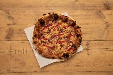 Kırmızı soğanlı Meksika pizzası, erimiş çedar peyniri, ahşap masada kırmızı biber şeritleri.