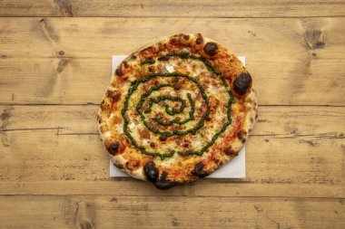 Karamelli soğanlı pizza, mozzarella peyniri ve beyaz kabartma kağıdında pesto sosu.
