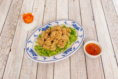 Kızarmış tavuk şeritleri susam tohumunda dövülmüş. Tatlı ve ekşi sosla birlikte. Buzdağı kıvırcığına batırmak için.