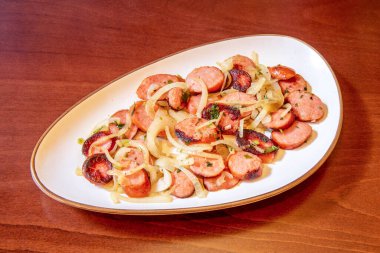 Kömürle kızartılmış Brezilya sucuğu dilimlenmiş soğan ve maydanoz.