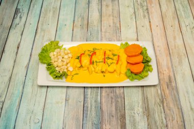 Pişmiş mısır, bol sarı sos ve beyaz tepside tatlı patates dilimleri ile Peru balık tiradito tarifi.