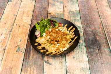 Salata tabağı, marul, doğranmış peynir, çıtır soğan, vişneli domates ve siyah tabakta turp dilimleri.