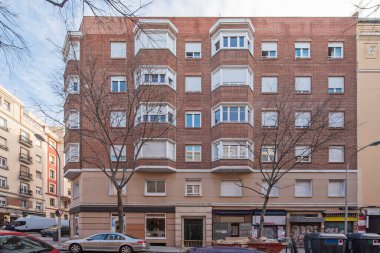 Yaprak döken ağaçlarla dolu bir kış günü büyük pencereli kırmızı kil tuğla bina cephesi