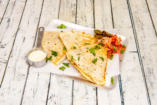 Synchronized Mexican quesadillas of melted cheese with pico de gallo and cream cheese with parsley and cilantro