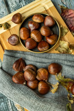 Klasik tabakta lezzetli kestaneler ve gri kumaş. Düşen yapraklarla dolu bir sonbahar