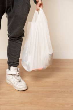 Naylon poşetli bir adam süpermarketten erzak taşıyor.