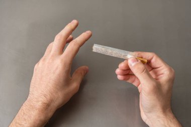 İnce pirinç kağıdıyla gülen eller sigarayı yuvarlıyor