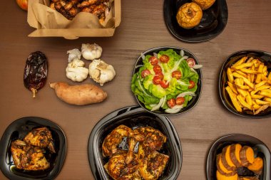 Pazar yemeklerinin üst görüntüsü, soslu kızarmış tavuk, marul ve domates salatası, ev yapımı cips ve kızarmış elma.