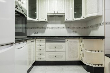 Kiralık kiralık ev mutfağı, beyaz kaplamalı dolaplar ve siyah tezgahlar.