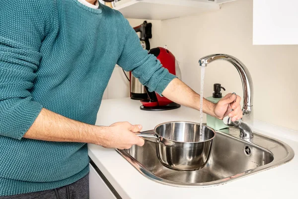 腕を持つ若い男はスパゲッティを沸騰させるために水で容器を充填ロールアップ — ストック写真
