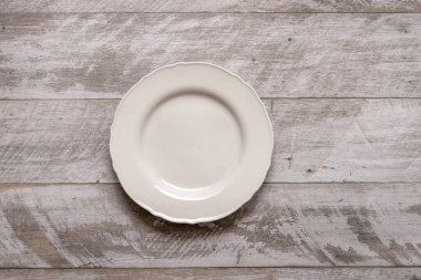 Gri ahşap bir masada güzel beyaz bir porselen tabak.