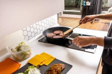 Ekmeği doldurmak için tavada et köftesi pişiren genç adamın elleri.