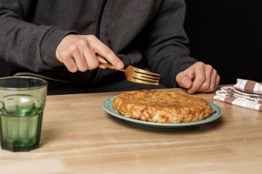 Genç bir adamın elinde altın bir çatal tutarken taze yapılmış patates omleti yemek için.