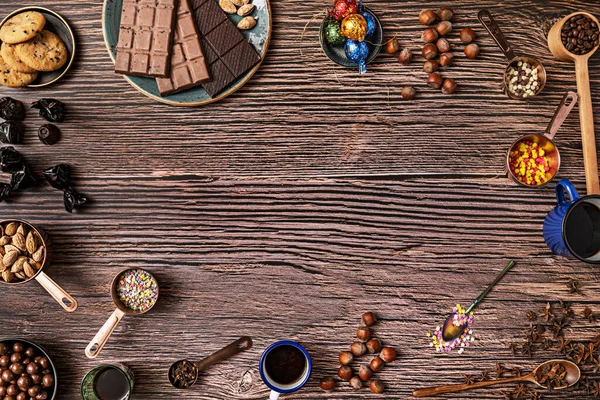 Still life of chocolates, roasted salted hazelnuts and almonds, orange juice, wooden plank table and chocolate cookies on wooden planks background
