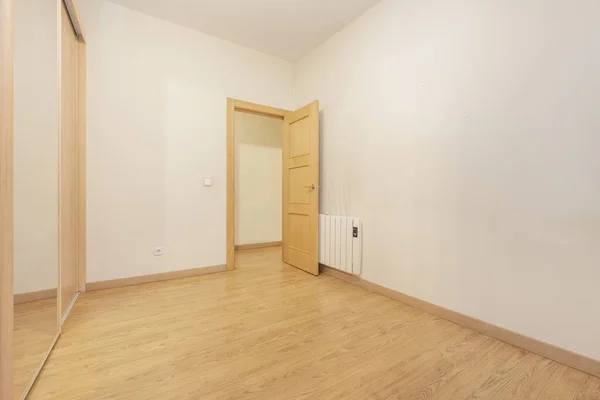 Empty bedroom with built-in wardrobe with mirrored door and electric heating