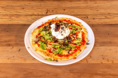 Burrata peynirli pizza, vişneli domates, roka ve taş fırında pişirilmiş serano jambonu.