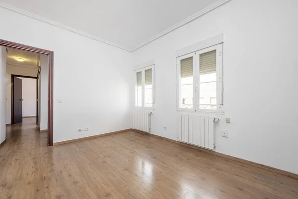 Unfurnished living room with white aluminum windows, chestnut wood flooring and aluminum radiators