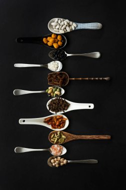 Fındık, tohum, baharat ve baklagillerle doldurulmuş farklı malzeme ve şekillerden oluşan sipariş edilmiş kaşıklar.