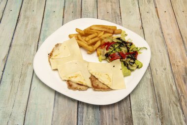 Peynirli domuz filetosu, patates kızartması, biberli salata, salatalık ve beyaz porselen tabakta balzamik sirke karışımı.