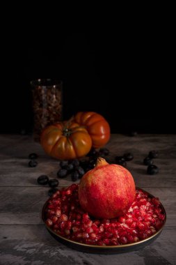 Nar, tahıl, yabanmersini, yıldız anason ve ahşap masadaki pembe domateslerle dolu bir hayat.