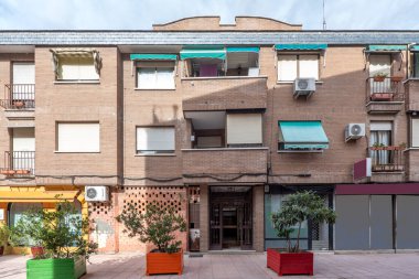 Kahverengi tuğlalı binaların ön cephesinde büyük, renkli, ahşap saksılar var.