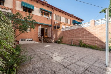 Kırmızı tuğlalı, merdivenleri, ağaçları ve bitkileri olan tek kişilik aile terası.