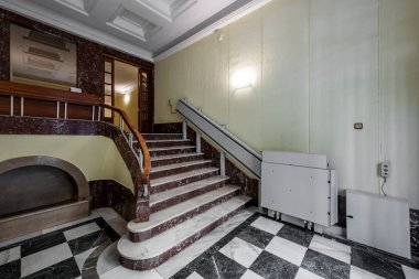 Mermer merdivenler tekerlekli sandalyeler için konut evlerine ve merdiven asansörlerine gidiyor.